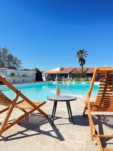 a table and two chairs next to a pool at L'auberge Camarguaise in Saintes-Maries-de-la-Mer