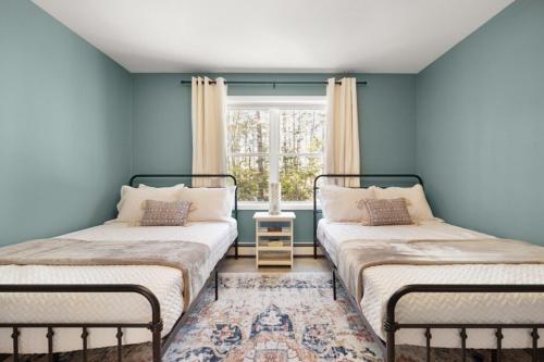 two beds in a blue room with a window at Maine Woods Retreat in Ellsworth