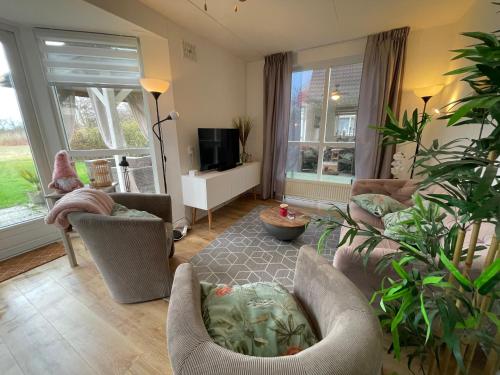 a living room with a couch and chairs and a tv at Gezellige vakantiewoning aan het water in Ewijk - recreational only no workers in Ewijk