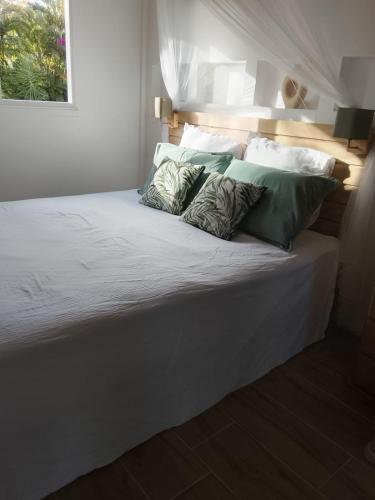 a large white bed with green pillows on it at Tialba Lodge in Sainte-Anne