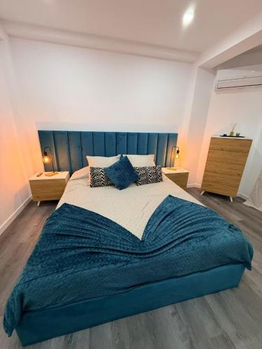 a bedroom with a large bed with a blue blanket at House Caparica in Costa da Caparica