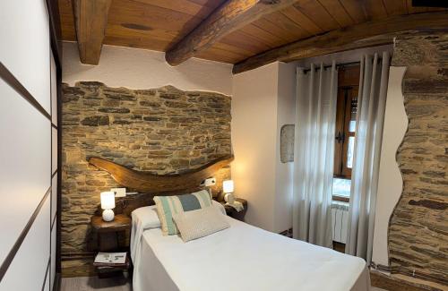 a bedroom with a bed and a stone wall at A Casa da Ponte in Lugo
