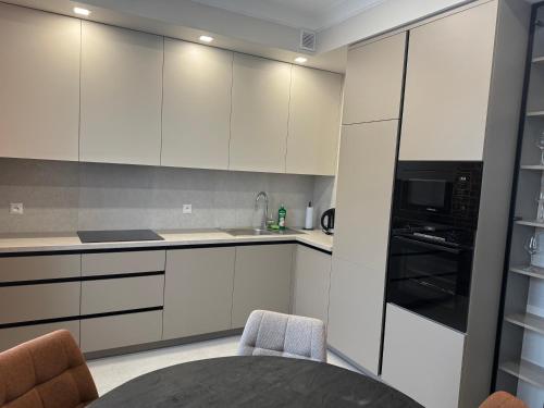 a kitchen with white cabinets and a black microwave at Apartament przy parku in Augustów