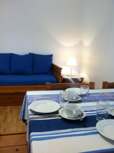 a table with plates and cups and a blue couch at Résidence Mes Amours d'Enfants - Les Villas du Lac in Soustons