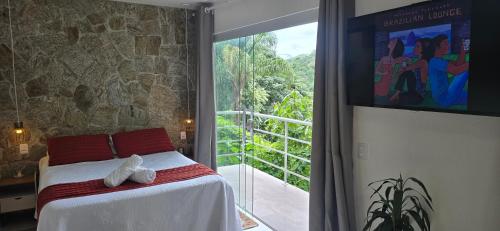 a bedroom with a bed and a large window at Estúdio Beija-flor Itaipava in Araras Petropolis