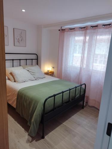 a bedroom with a bed with a green blanket and curtains at Pretodomar2 in A Coruña
