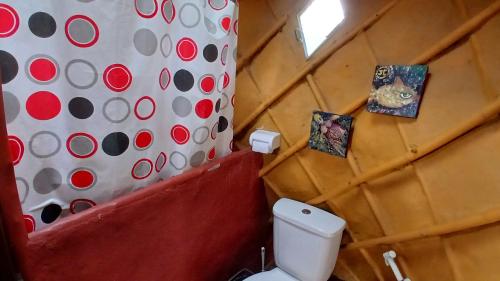a bathroom with a toilet with two pictures on the wall at Ananda Matha YURTA - Vale do Capão in Palmeiras