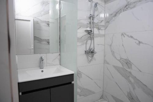 a white bathroom with a sink and a shower at Hotel Joana in Prizren