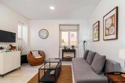 a living room with a couch and a clock on the wall at Doormans House city center by Homeful Homes in Lisbon