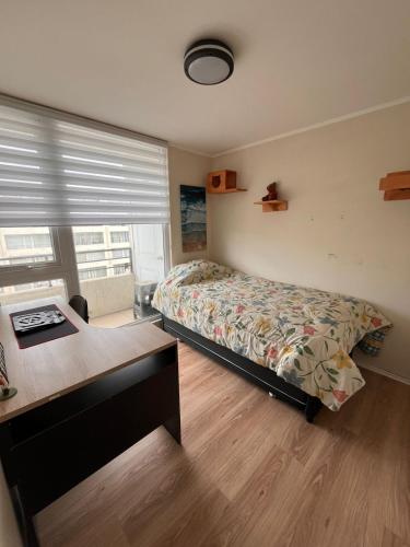 a bedroom with a bed and a desk and a window at Lindo Brisas in Talcahuano