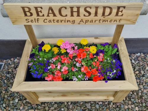 a garden in a wooden box with a sign at Beachside Apartment in Bangor