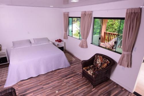 a bedroom with a bed and a chair and windows at Angatu Amazon Jungle Lodge in Iranduba