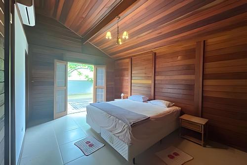 a bedroom with a bed with wooden walls and a window at Quintal da Serra in Morretes