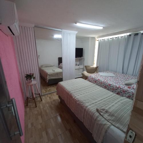 a hotel room with two beds and a mirror at Hospedagem Setúbal in Recife