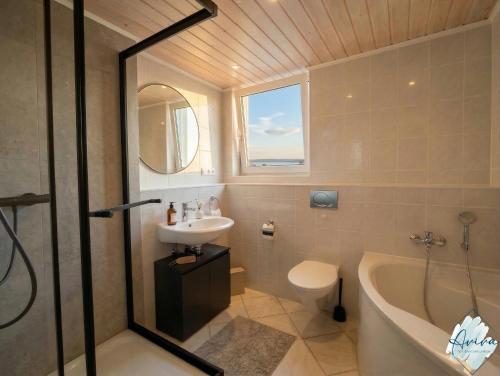a bathroom with a sink and a tub and a toilet at Aviva SEEPANORAMA - Großzügige 85m Wohnung mit Bodenseeblick in Bodman-Ludwigshafen