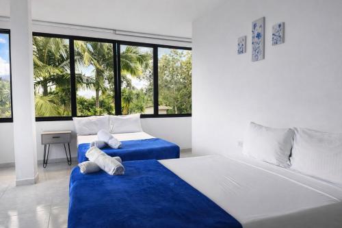 a bedroom with two beds with blue sheets and windows at Hotel Mirador Cielo Azul in Horizonte