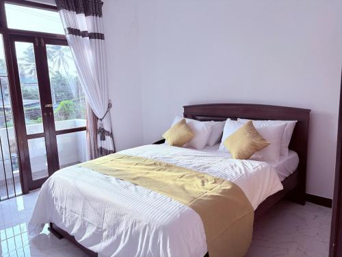 a bedroom with a bed with white and yellow sheets at Edelweiss Living Negombo in Negombo