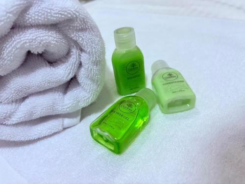 two bottles of green liquid next to a towel at Edelweiss Living Negombo in Negombo
