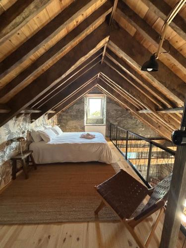 a attic bedroom with a bed and a chair at Cá Por Casa Pico-Criptoméria in Prainha de Baixo