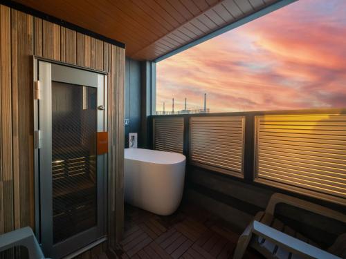 a bathroom with a tub and a view of a sunset at Kanohotel and Cabin Chiba Soga in Chiba
