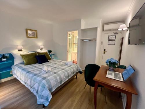 a bedroom with a bed and a desk with a laptop at Hôtel La Sanguine in Paris