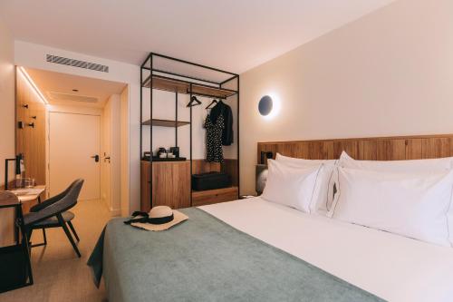 a bedroom with a bed with a hat sitting on it at Hotels 705 O'Porto Hotel in Porto