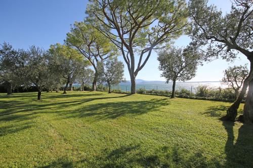 a park with trees and the water in the background at Villa Elena in Manerba del Garda