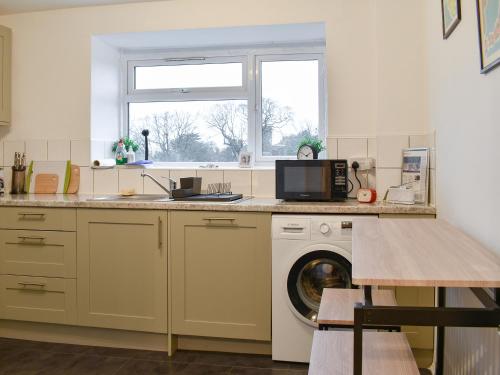 a kitchen with a washing machine and a window at Tankerton Heights in Whitstable