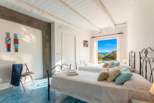 a bedroom with two beds and a large window at Villa Emmeline fronte mare 5 camere 6 bagni infinity pool WiFi per 12 persone in Alghero