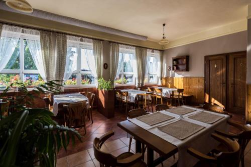 a dining room with tables and chairs and windows at Penzion Janová in Ostrava