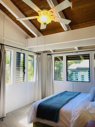 a bedroom with a ceiling fan and two windows at Princeville North Shore Retreat - 1200 SF, Lanai, Loft & Kitchen in Princeville
