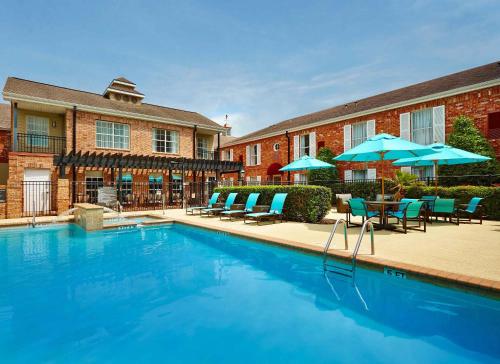 a swimming pool with chairs and umbrellas in front of a building at Extended Stay America Suites - Houston - Galleria in Houston