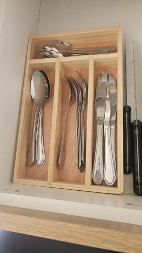 a wooden tray with silver utensils on a shelf at Departamento Centro Osorno in Osorno