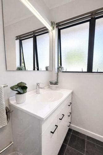 a bathroom with a white sink and two windows at Redwoods Retreat Rotorua Private 3BR Home in Rotorua
