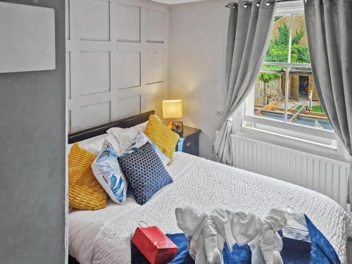 a bedroom with a bed with colorful pillows and a window at Cosy Studio in Hampton Hill short Walk to Bushy Park with Free Parking and WiFi and Pets welcome in Hampton Hill