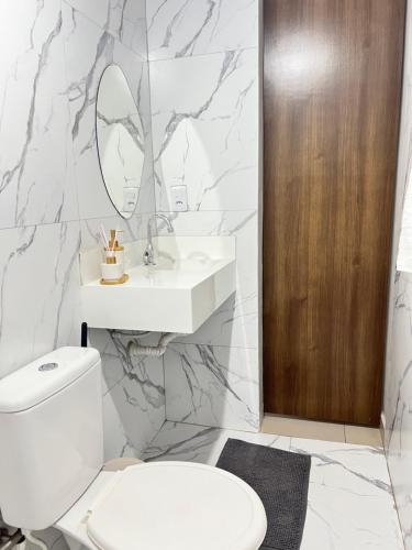 a bathroom with a toilet and a sink and a mirror at Apt estiloso 03 in Paragominas