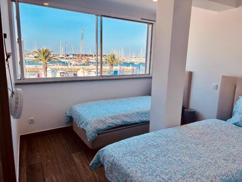 a bedroom with two beds and a large window at Guest House Vasco da Gama in Lagos