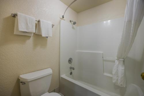 a bathroom with a toilet and a shower with towels at Suburban Studios Canon City in Canon City