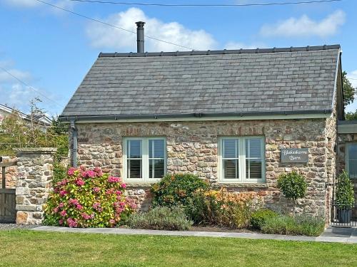 a stone house with flowers in front of it at Blakeskerra Barn in Kenfig