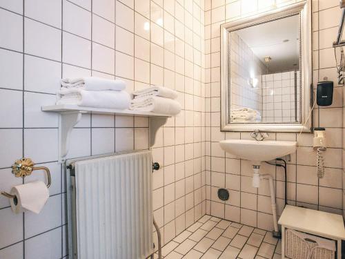 a white tiled bathroom with a sink and a mirror at Holiday home in Marstal in Brovst