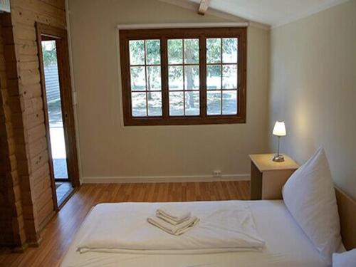 a bedroom with a white bed with a window at Bernsteinsee Home and Ferien Forest Chalet in Sassenburg