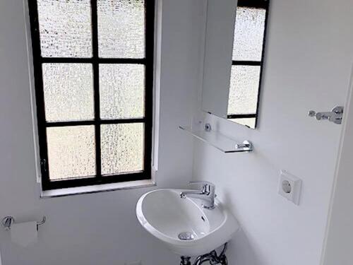 a white bathroom with a sink and a mirror at Bernsteinsee Home and Ferien Small Forest Chalet in Sassenburg