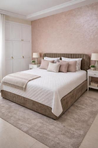 a bedroom with a large bed with white and pink pillows at appartement luxe in Berkane