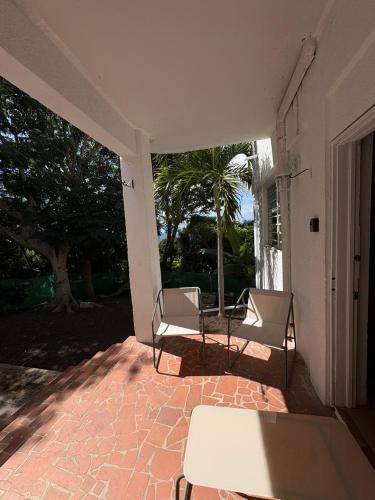 a patio with two chairs and a table on a porch at Cocoon apartment with garden, quiet in Simpson Bay
