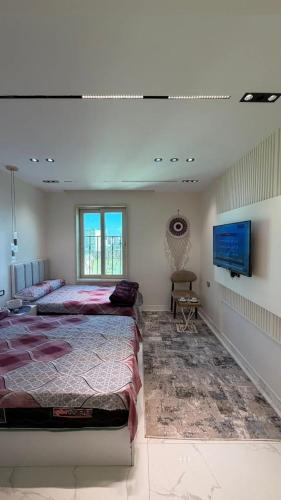 a bedroom with a large bed and a flat screen tv at فندق العجمي 100 in 6th Of October
