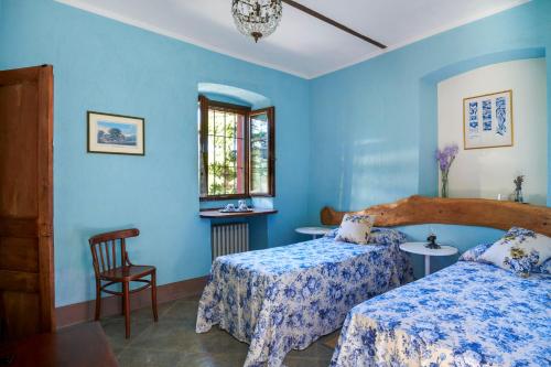 a blue bedroom with two beds and a chair at Cascina Sant'Eufemia in Sinio