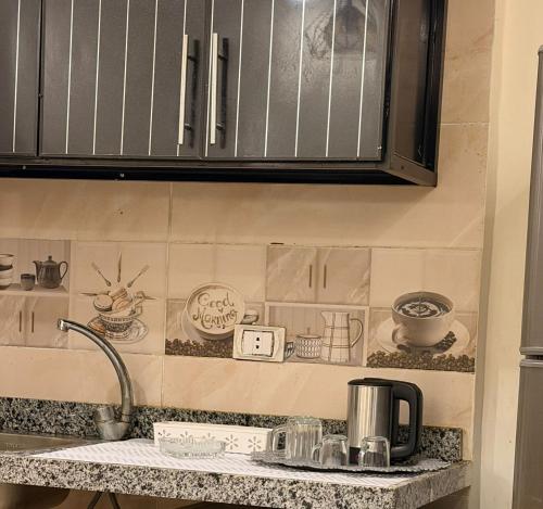 a kitchen counter with cups and dishes on the wall at فندق العجمي 100 in 6th Of October