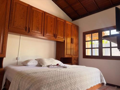 a bedroom with a bed with wooden cabinets and a window at BEACH HOUSE pé na areia in Santa Cruz Cabrália