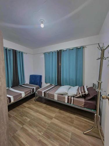 two beds in a room with blue curtains at BCDCrib in Bacolod