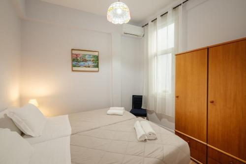 a white bedroom with a large bed and a wooden cabinet at Venetian Balcony , Old Town Corfu in Corfu